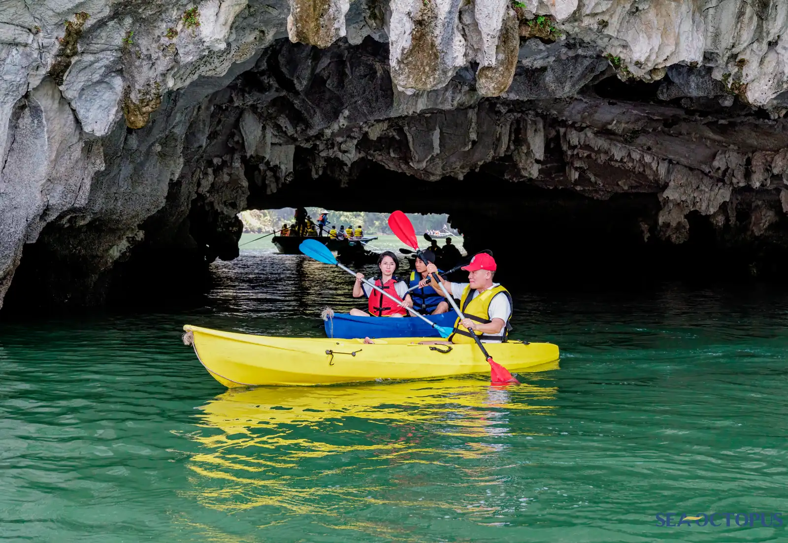 Du khách chèo kayak len qua vòm hang đá ra vùng nước xanh ngọc